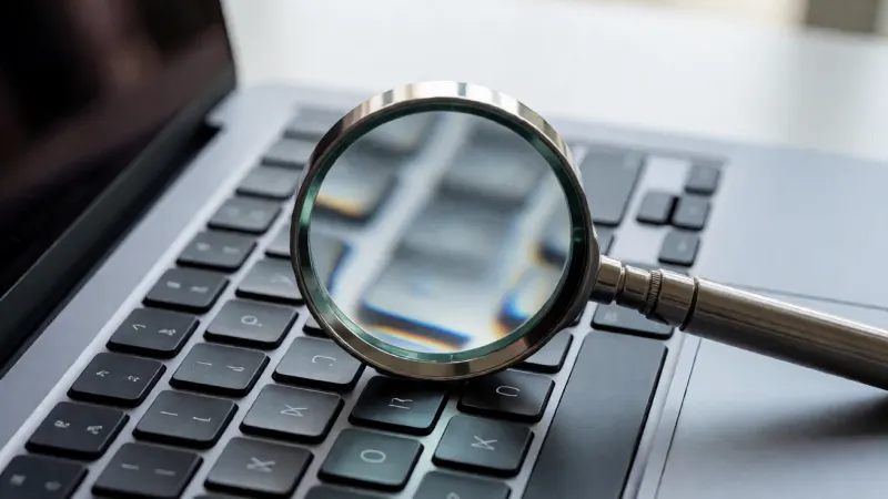 Magnifying glass examining an online travel booking website on a laptop screen.