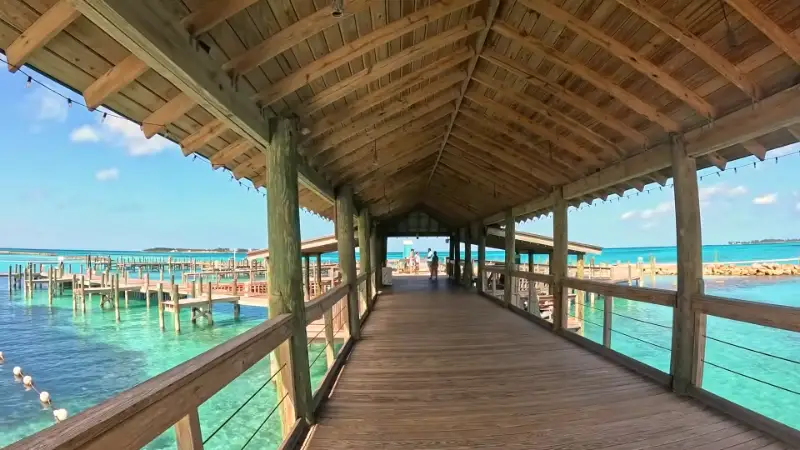 Aerial view of a long wooden pier extending into incredibly clear, turquoise ocean water in Nassau